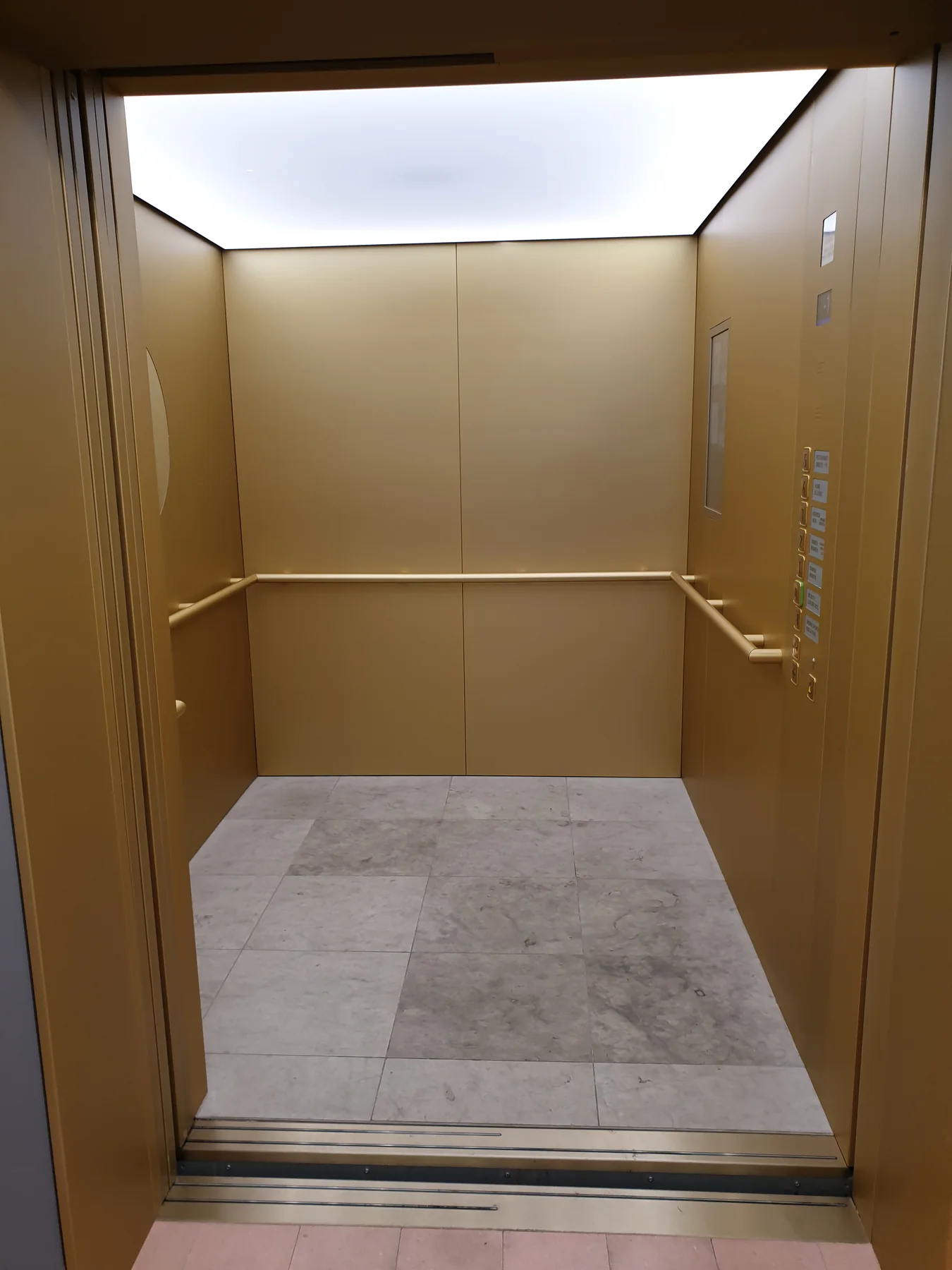 Front view of a gold-toned elevator cabin at Oberpollinger