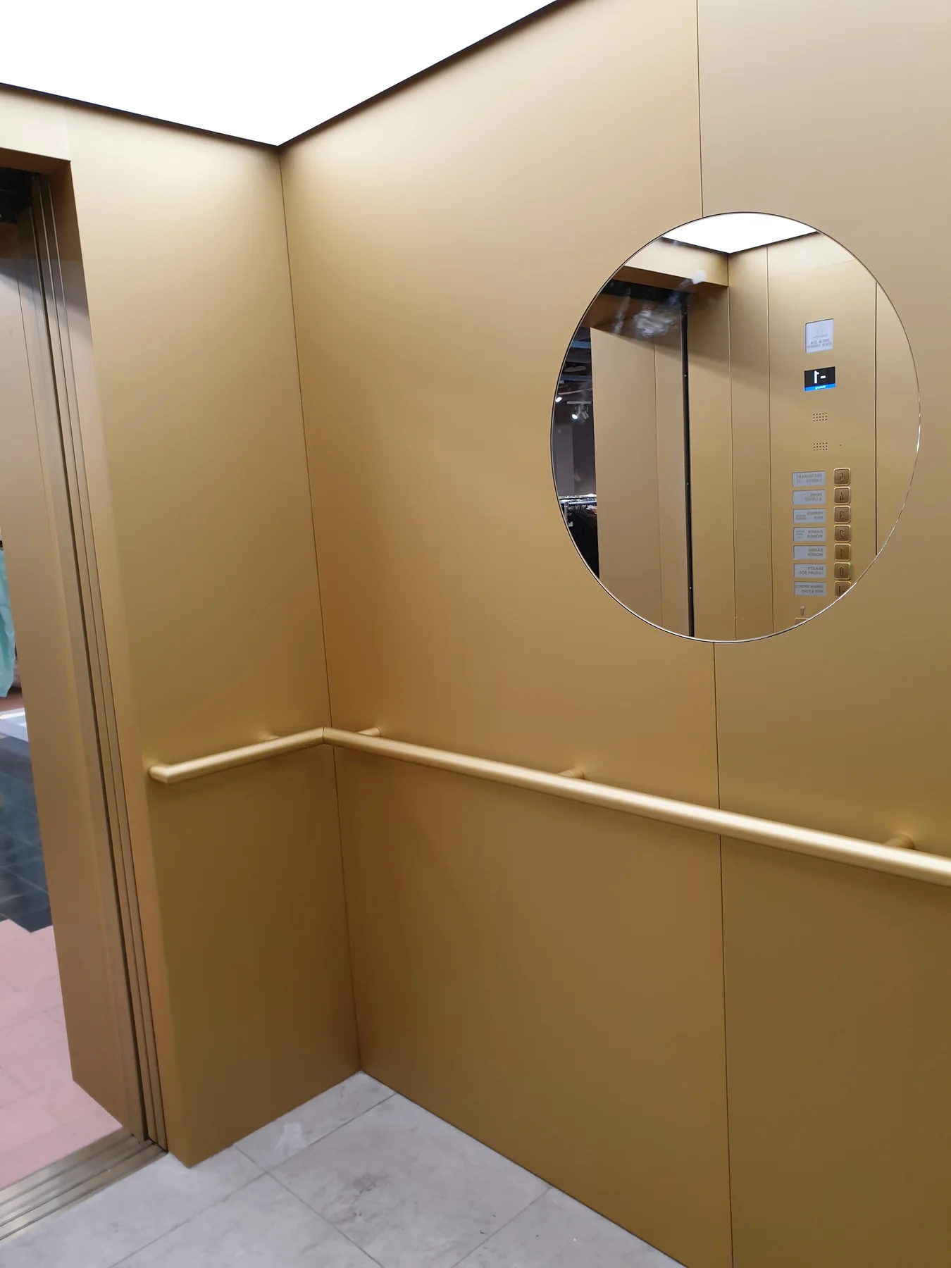 Round mirror and handrail inside an Oberpollinger elevator cabin